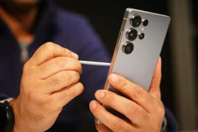 Close-up of a man interacting with a smartphone using a stylus, indoors.