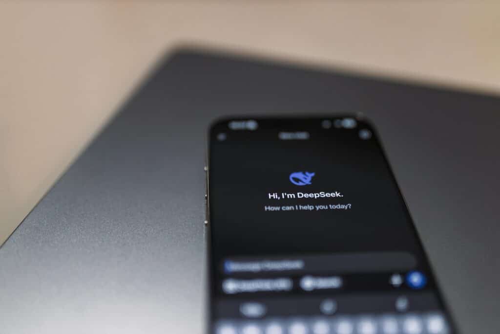 Close-up of a smartphone with AI assistant interface on screen over a laptop.