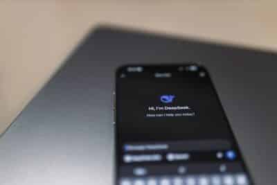 Close-up of a smartphone with AI assistant interface on screen over a laptop.